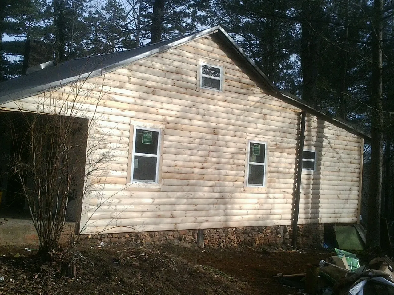 New log siding and dark metal roofing on a gable end in Justice