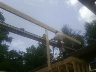 Carpenter setting a ridge beam over a new addition frame — Ice Dam Removal by Roofing Brothers in Justice