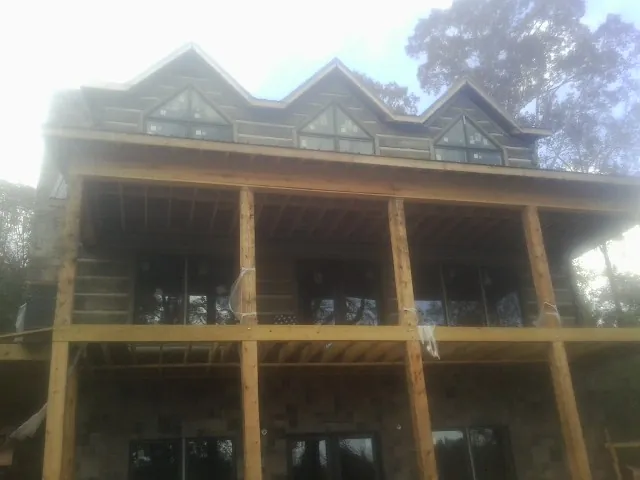 Dormers and porch framing on a large log home under construction — Roof Coating work by our crew in Justice