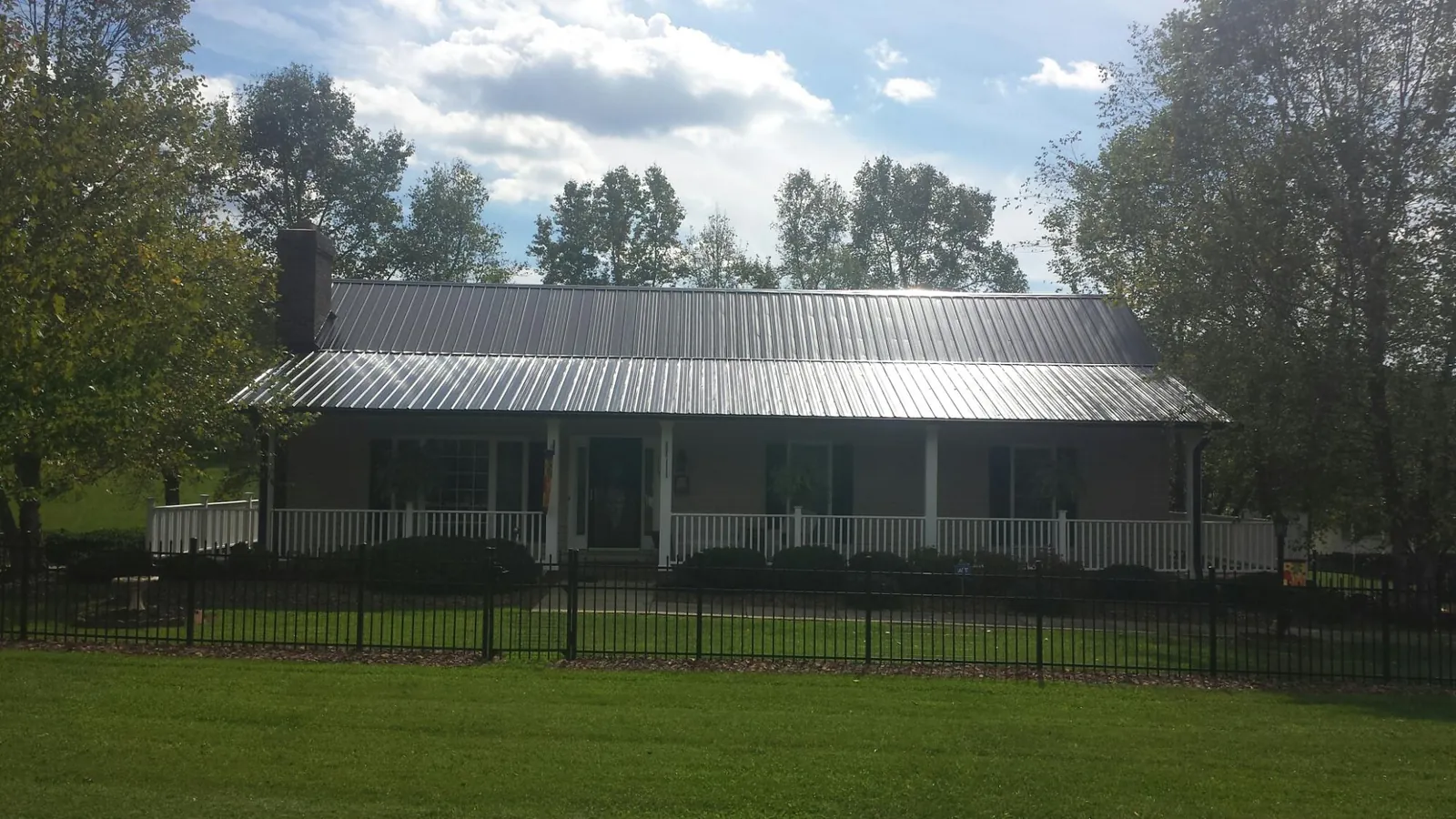 Gray metal roof on a brick ranch with a full width front porch — Gutter Guard Installation work by our crew in Justice
