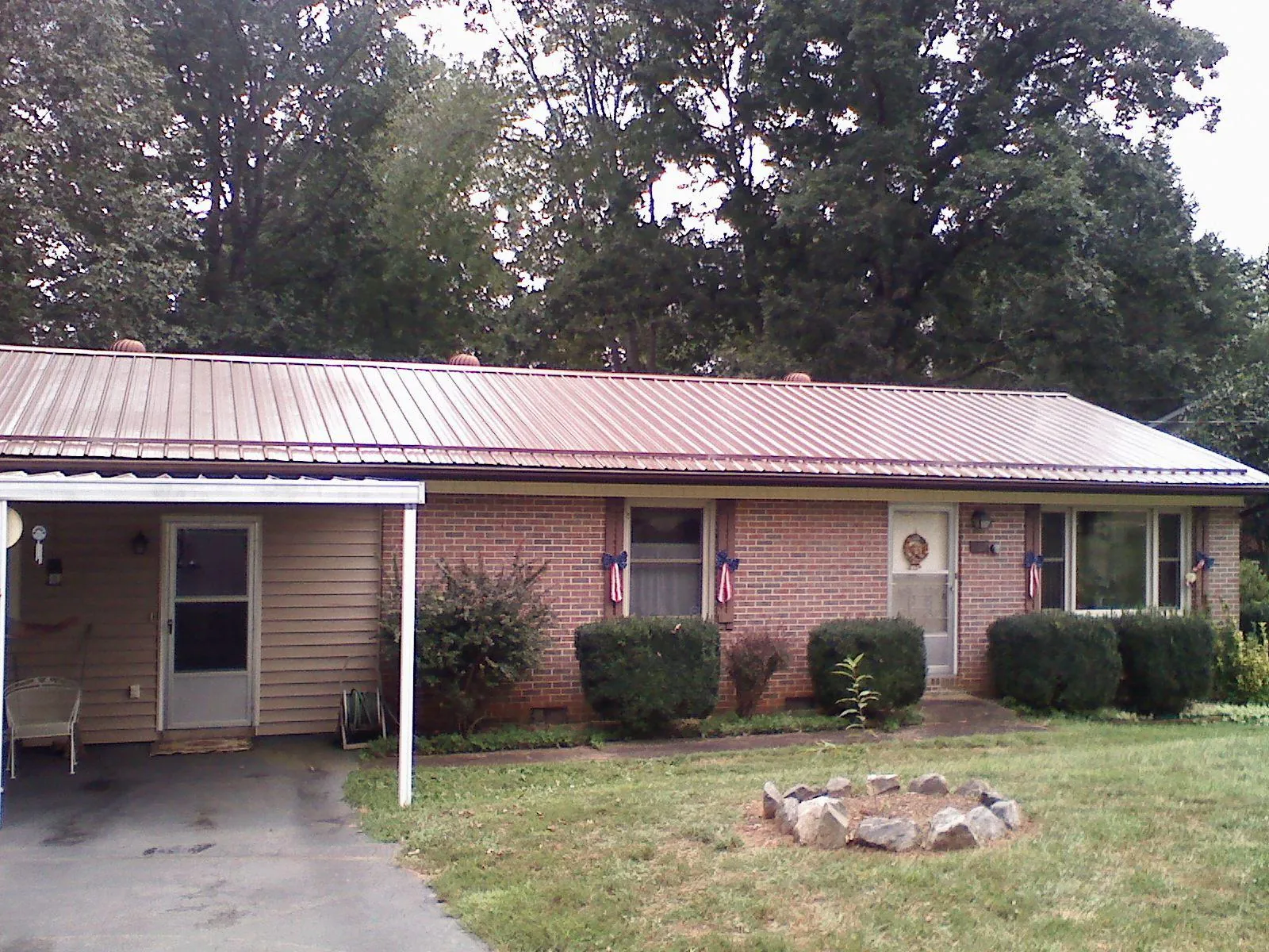 Bronze metal roof and carport on a brick ranch home — Roof Repair work by our crew in Justice