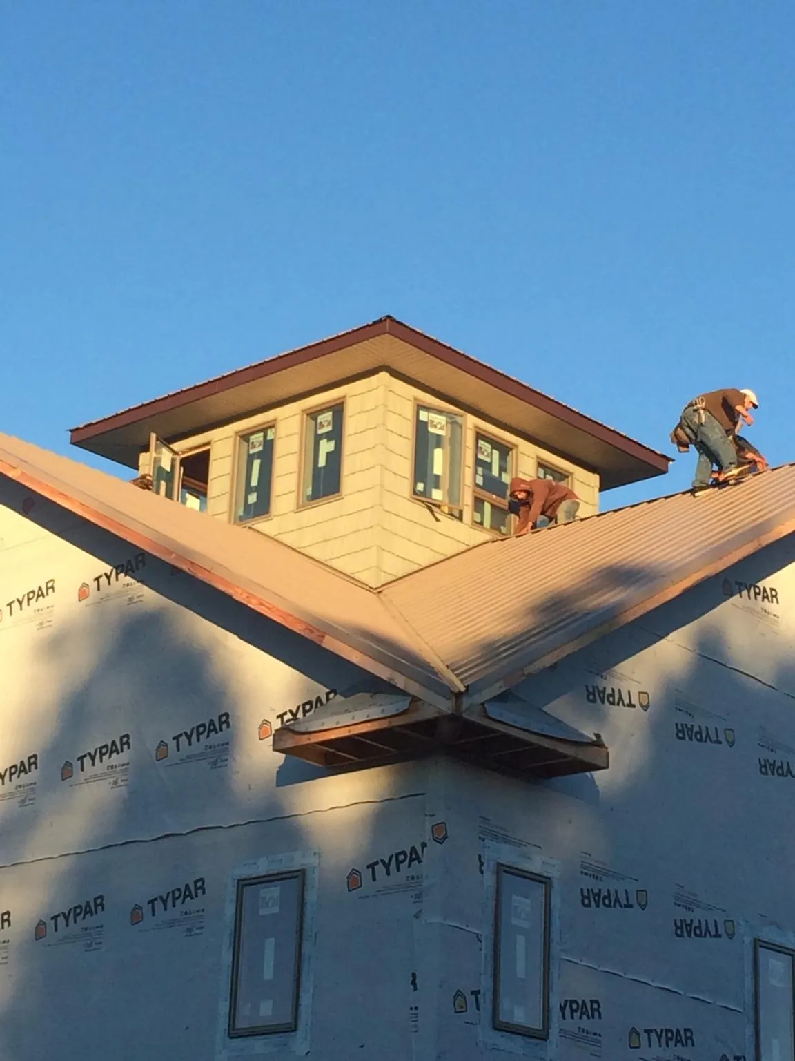 Roofers working around a rooftop cupola on a new metal roof at sunset — Roof Waterproofing in Justice by Roofing Brothers